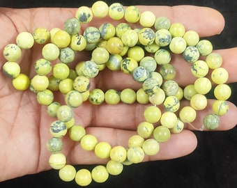 Peut inclure: Un brin de perles de pierres précieuses jaunes et vertes. Les perles sont rondes et ont un aspect marbré.