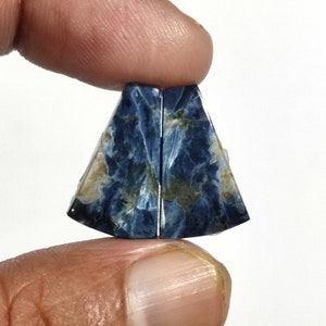 May include: A pair of blue and white tiger's eye cabochons, cut in a triangular shape. The stones have a chatoyant effect, with a shimmery, iridescent quality.