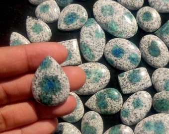 May include: A collection of polished, teardrop-shaped gemstones with a white and blue speckled pattern. The stones have a variety of sizes and shapes.