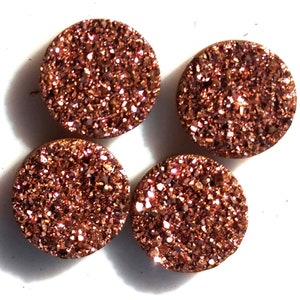 May include: Four round, copper-colored, sparkly, glittery, flatback cabochons. These cabochons are perfect for crafting and jewelry making.