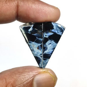 May include: A blue and black tiger's eye gemstone cabochon cut in a triangular shape.