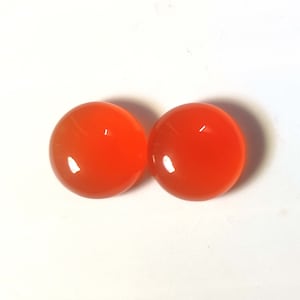 Pode incluir: Duas pedras preciosas redondas de cornalina laranja. As pedras preciosas são lisas e polidas.