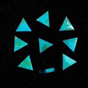 Puede incluir: Diez piedras turquesa en forma de triángulo sobre un fondo negro. Las piedras son de varios tonos de azul y verde.