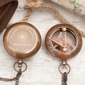 May include: A brass compass with a chain and a leather case. The compass has a sun dial and a compass rose. The compass is engraved with the text "To guide our adventures, Pierce - Nelson, Est. 7.21.2012".