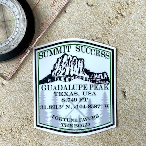 May include: A white sticker with green borders and a black and white illustration of a mountain range. The text on the sticker reads "Summit Success", "Guadalupe Peak", "Texas, USA", "8,749 ft", "31.8913° N, -104.8587° W", "Fortune Favors The Bold", and "www.gatewayraft.com".