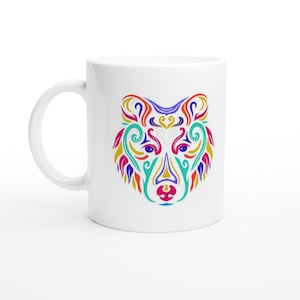 May include: White ceramic mug with a colorful, abstract wolf design. The wolf's face is made up of swirls and lines in shades of red, orange, yellow, blue, green, and purple.