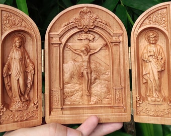 May include: A wooden triptych with three panels. The center panel depicts a carved image of Jesus Christ on the cross. The left panel shows the Virgin Mary and the right panel shows Saint Peter. The panels are decorated with intricate carvings.