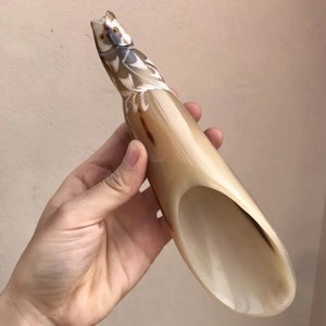 Op de afbeelding: Een gegraveerd hoorn met een gedetailleerd uil ontwerp. De hoorn is lichtbruin met donkerbruine accenten en een witte binnenkant. De uil is realistisch gegraveerd met ingewikkelde details.