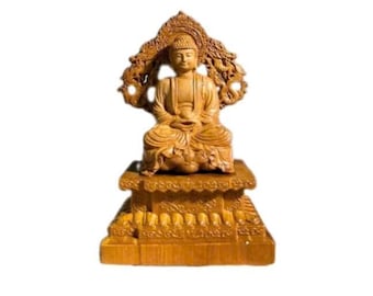 May include: A light brown wooden statue of a seated Buddha figure. The figure is positioned on a rectangular tiered base with intricate carvings and is backed by an ornate, detailed mandorla featuring swirling patterns and motifs.