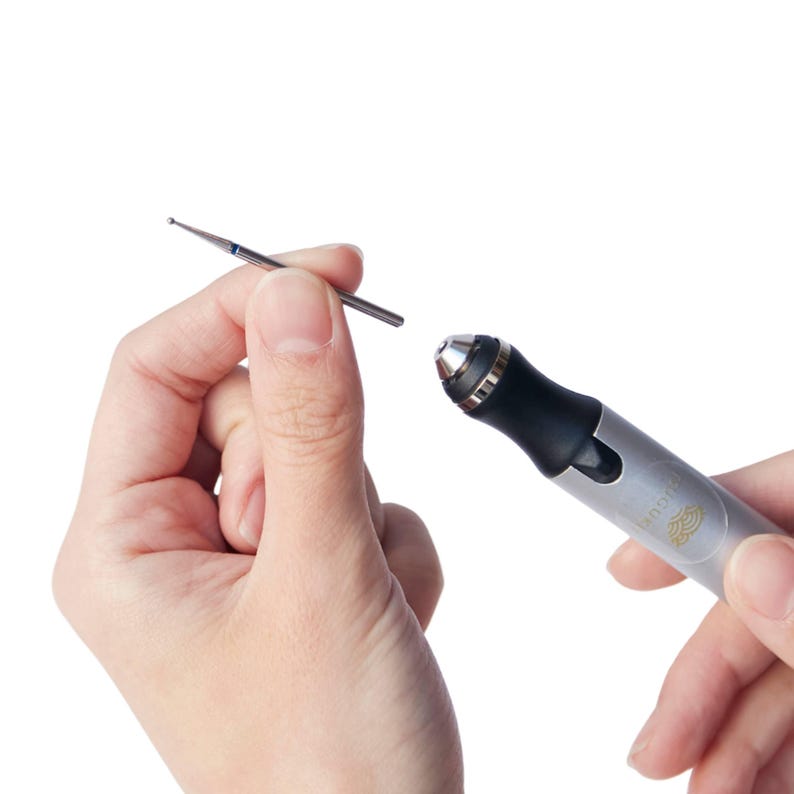 May include: A silver and black electric nail drill with a silver metal bit attached. The drill has the word "Impress" printed on the side.