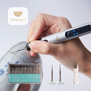 Peut inclure: Un outil rotatif électrique argenté avec un écran LED bleu et un câble de charge USB. L'outil est utilisé pour sculpter un bol en céramique. L'outil est livré avec un jeu de 20 forets différents et deux forets supplémentaires.