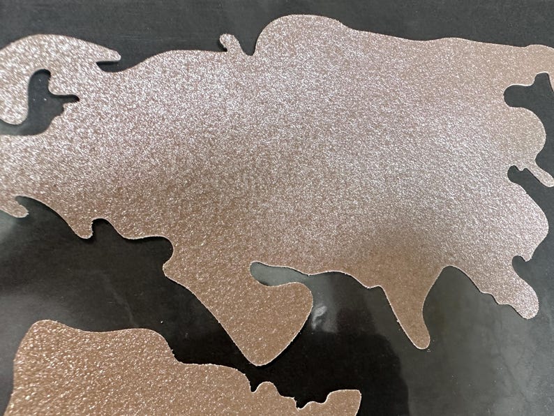 May include: A silver glitter-covered map of the world with a black background.