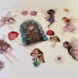May include: A collection of die-cut stickers featuring a brown wooden door with a heart-shaped window, surrounded by stone and floral accents. The set includes various fairies with wings, red and brown mushrooms, and small individual flower blossoms.