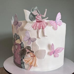 May include: A white cake decorated with fondant butterflies and fairies. The cake features a small pink door with a heart-shaped window and a stone wall.