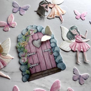 May include: A set of fairy door and butterfly decorations. The door is pink with a heart-shaped window and is surrounded by green vines and flowers. The butterflies are in various colours, including pink, purple, and yellow.