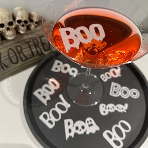 May include: A black tray with white "BOO!" stickers on it. A martini glass with a red drink and a white "BOO!" sticker on it sits on the tray.