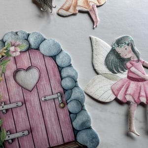K&ouml;nnte beinhalten: Eine skurrile Illustration mit einer rosa Feent&uuml;r mit herzf&ouml;rmigem Fenster, umgeben von blauen Steinen und floralen Akzenten. Eine Fee mit rosa Kleid, Fl&uuml;geln und Blumenkranz ist ebenfalls abgebildet. Das Bild hat ein M&auml;rchen-Thema.
