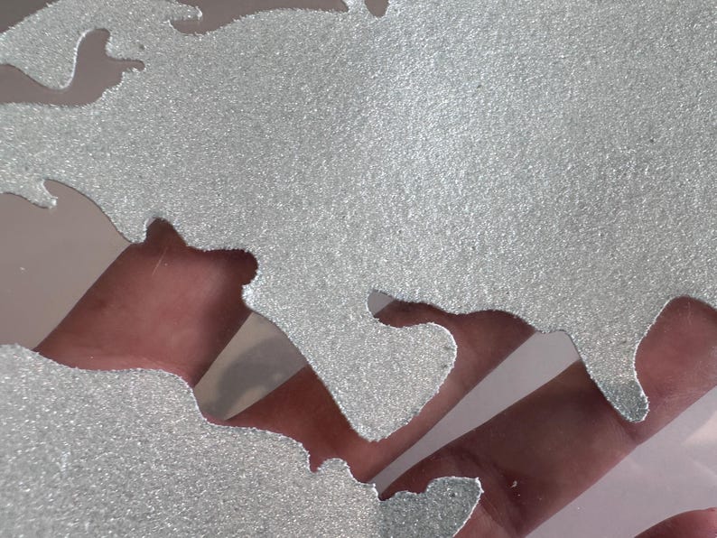 May include: A silver glitter world map stencil. The stencil is made of a thin, flexible material and has a detailed outline of the continents and oceans.