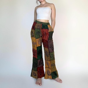 May include: A pair of wide-leg pants with a patchwork design featuring various colors and patterns, including green, red, yellow, and brown. The pants have a high waist and a flared leg.