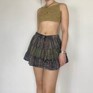 May include: A multi-layered skirt with a dark green, black and brown colour scheme. The skirt has a drawstring waist and a ruffled hem.