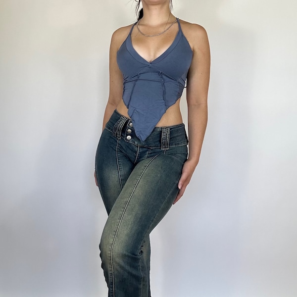Könnte beinhalten: Ein blaues Halstuch mit Kreuzdesign und einem langen, fließenden Vorderteil. Das Oberteil wird mit dunkelblauen Jeans kombiniert.