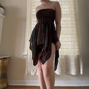 Puede incluir: Un vestido marrón y negro sin tirantes con un diseño estampado. El vestido tiene un corpiño ajustado y una falda fluida.