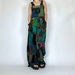 May include: A long, patchwork overall dress with a variety of colors and patterns, including green, blue, and brown. The dress has a simple, sleeveless design and a relaxed fit.