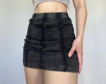 Puede incluir: Minifalda negra con diseño de patchwork. La falda está hecha de una tela texturizada y presenta costuras visibles. La prenda tiene una cintura alta y una silueta ajustada, adecuada para ropa casual.