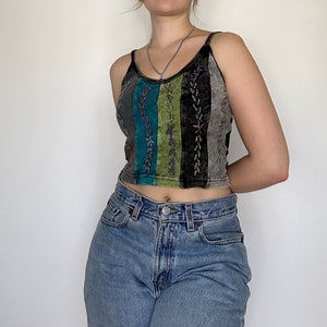 May include: A cropped tank top with a multi-coloured striped design and embroidered details. The top is made of a soft, lightweight fabric and has a relaxed fit.