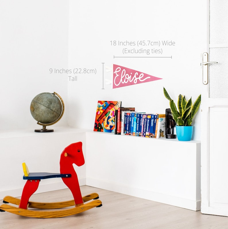 Peut inclure: Une banni&egrave;re en feutre rose avec le nom "Eloise" &eacute;crit en lettres blanches. La banni&egrave;re mesure 45,7 cm de large et 22,8 cm de haut.
