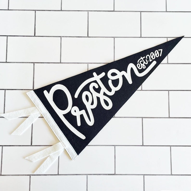 Peut inclure: Un fanion en feutre noir avec l'inscription "Preston est. 2007" en blanc. Le fanion a des liens blancs en bas.