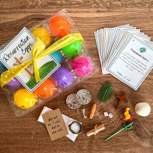 以下が含まれることがあります： カラフルなプラスチックのイースターエッグ、黄色のリボン、そして「Resurrection Eggs」と書かれたタグが入った透明なプラスチックパッケージ。カード、コイン、葉、十字架、その他の小さな宗教的シンボルも含まれています。