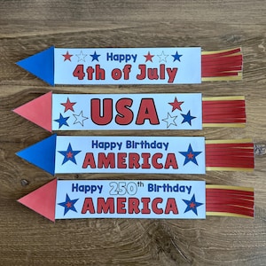 Pode incluir: Quatro decorações de papel em forma de foguete nas cores vermelho, branco e azul. Cada uma tem uma ponta, um corpo retangular com texto e caudas com franjas vermelhas e douradas. O texto inclui Happy 4th of July, USA, Happy Birthday AMERICA e Happy 250th Birthday AMERICA.
