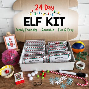 May include: A 24 Day Elf Kit in a cardboard box with red and green text. The kit includes small activity cards, a miniature easel with an elf illustration, a pink paper umbrella, a bowl with a red mushroom, a playing card, white pom-poms, small glasses, snowflake cutouts, a candy cane, a marker, a ball, and green toy soldiers.