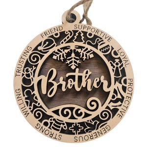 May include: A round wooden ornament with a brown wood center and a black and white design around the edge. The center says "Brother" in a decorative font. The words around the edge are "Trusting, Willing, Strong, Generous, Protective, Loyal, Supportive, Friend".