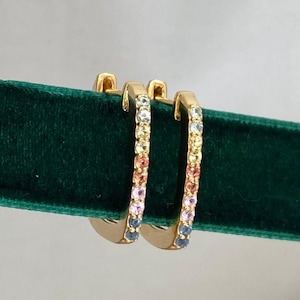 May include: A pair of gold hoop earrings with a rainbow of small gemstones set around the hoop.