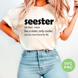 以下が含まれることがあります： 白いTシャツに「seester」という言葉が「妹のような、もっとクールな」と定義されています。テキストは黒で、シャツはブロンドの長い髪と青いジーンズを着用した人が着ています。