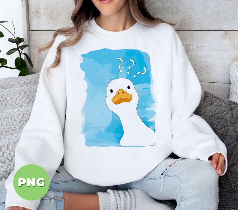 May include: A white sweatshirt with a blue watercolor design featuring a cartoon goose with a confused expression and question marks above its head. The text '??' is printed on the sweatshirt.