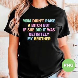 May include: Black t-shirt with the text "MOM DIDN'T RAISE A BITCH BUT IF SHE DID IT WAS DEFINITELY MY BROTHER" in a rainbow gradient font. The shirt is a crew neck style.