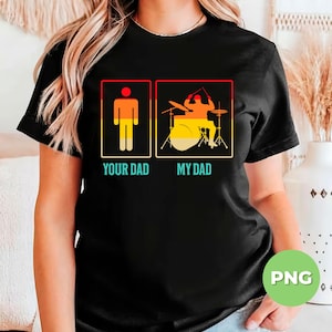 Puede incluir: Camiseta negra con un gráfico de dos figuras de palo. La figura de la izquierda está etiquetada como "Your Dad" y la figura de la derecha está tocando la batería y etiquetada como "My Dad".
