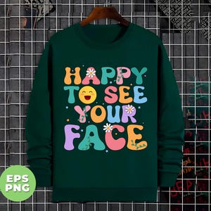 May include: A dark green sweatshirt with a colorful graphic print that says "Happy to see your face". The graphic features a smiling emoji with flowers and vines.