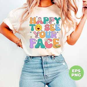 May include: A white t-shirt with the text "HAPPY TO SEE YOUR FACE" in colorful, outlined letters with flowers and stars.