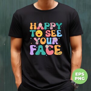 May include: A black t-shirt with a colorful graphic that says "Happy to see your face". The graphic features a smiling emoji, flowers, and vines.