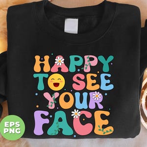 May include: Black sweatshirt with a colorful graphic design that says "Happy to see your face". The graphic features a smiling emoji, flowers, and vines.