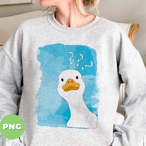 May include: A gray sweatshirt with a white duck with a blue watercolor background. The duck has a confused expression and question marks above its head. The text on the sweatshirt reads '???'.