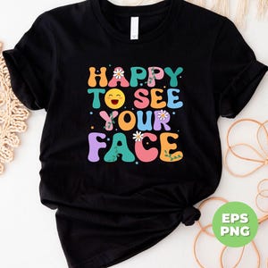 May include: Black t-shirt with a colorful graphic that says "Happy to see your face" with a smiley face and flowers.