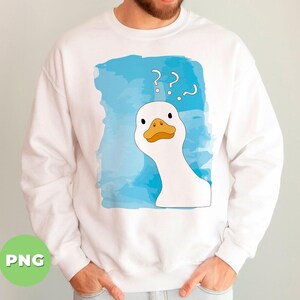 May include: White sweatshirt with a blue watercolor background and a white goose with a yellow beak and orange feet. The goose is looking to the right and has question marks above its head.