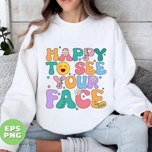 May include: White sweatshirt with a colorful graphic that says "Happy to see your face" with a smiley face and flowers.