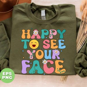 May include: Green sweatshirt with a retro-style graphic that says "Happy to see your face" in colorful letters with a smiling emoji and flowers.