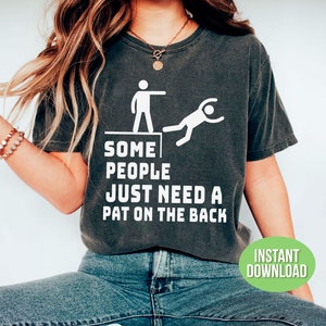 Pu&ograve; includere: T-shirt grigio scuro con la scritta "SOME PEOPLE JUST NEED A PAT ON THE BACK" e una grafica di una persona che ne spinge un'altra gi&ugrave; da un bordo. Un cerchio verde con "INSTANT DOWNLOAD" &egrave; in basso a destra.